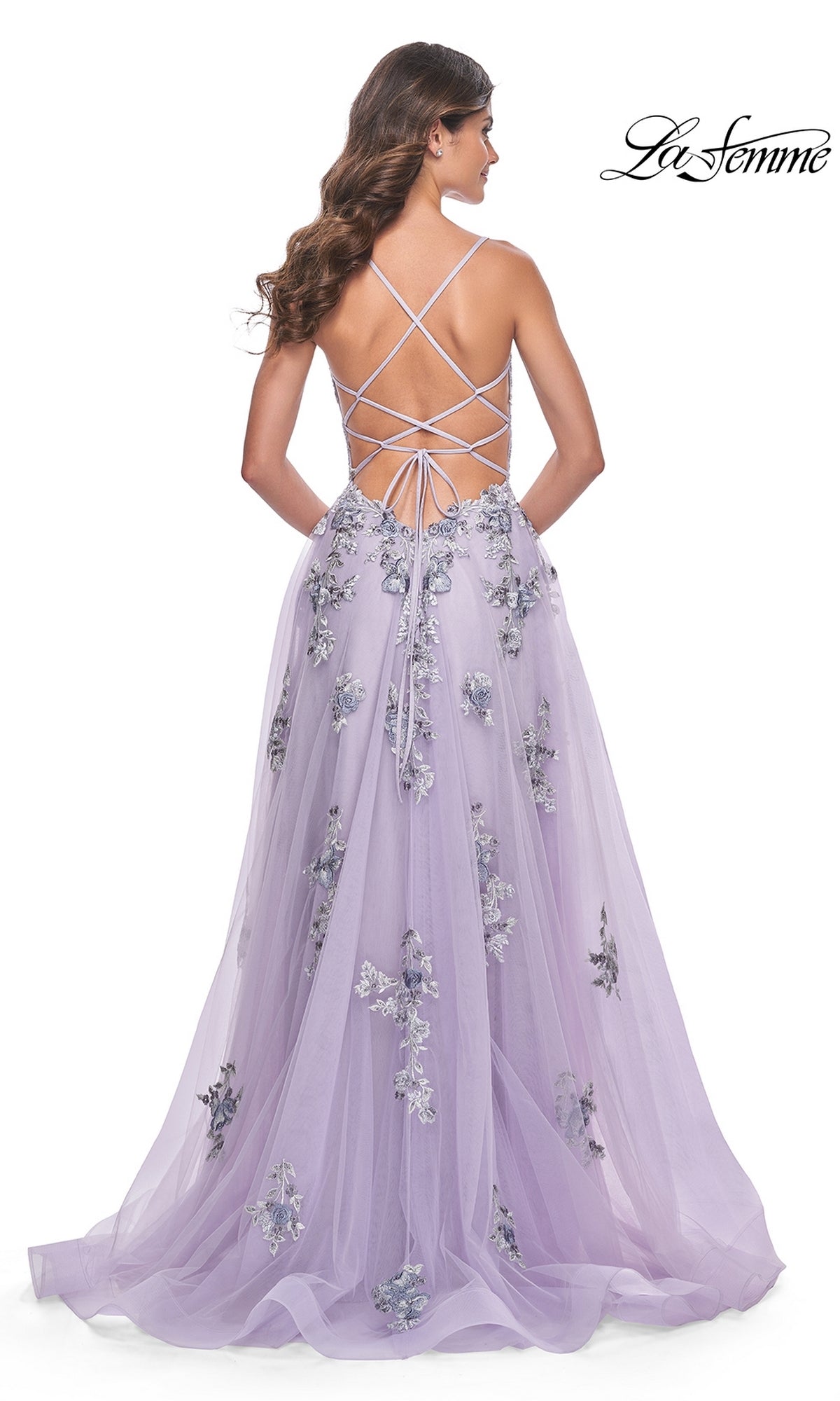 A woman in the La Femme Long Lavender A-Line Prom Dress 32221 with floral embroidery and an open, crisscross lace-up back stands facing away.